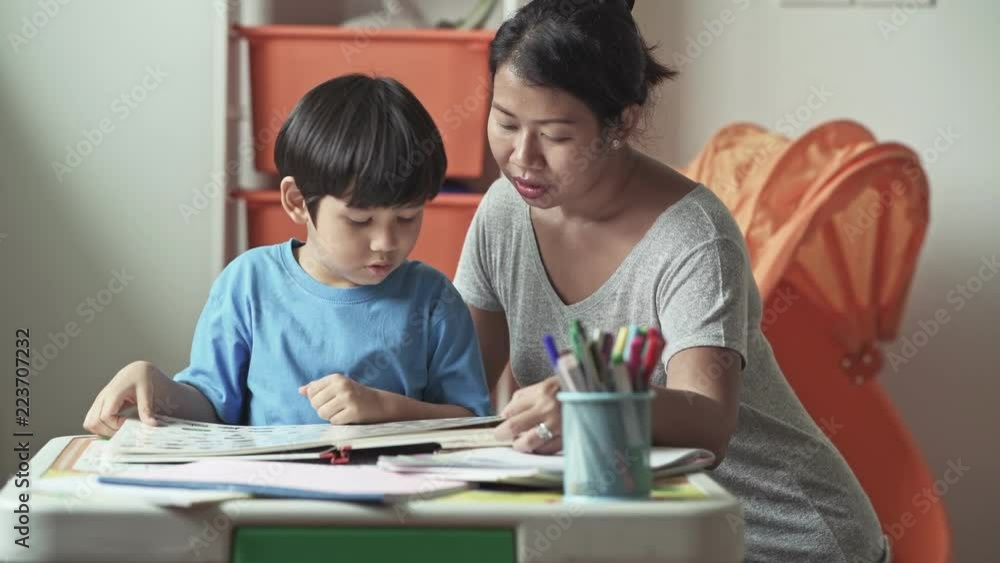 Children homework. Young mixed race boy doing homework in terrace at home. Reading book with his mother. Happy mood. Back to school concept. Children homework. Young mixed race boy doing homework in terrace at home. Reading book with his mother. Happy mood. Back to school concept.