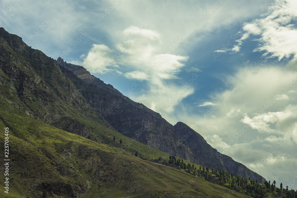 overgrown with green grass mountainside and blue sky overgrown with green grass mountainside and blue sky