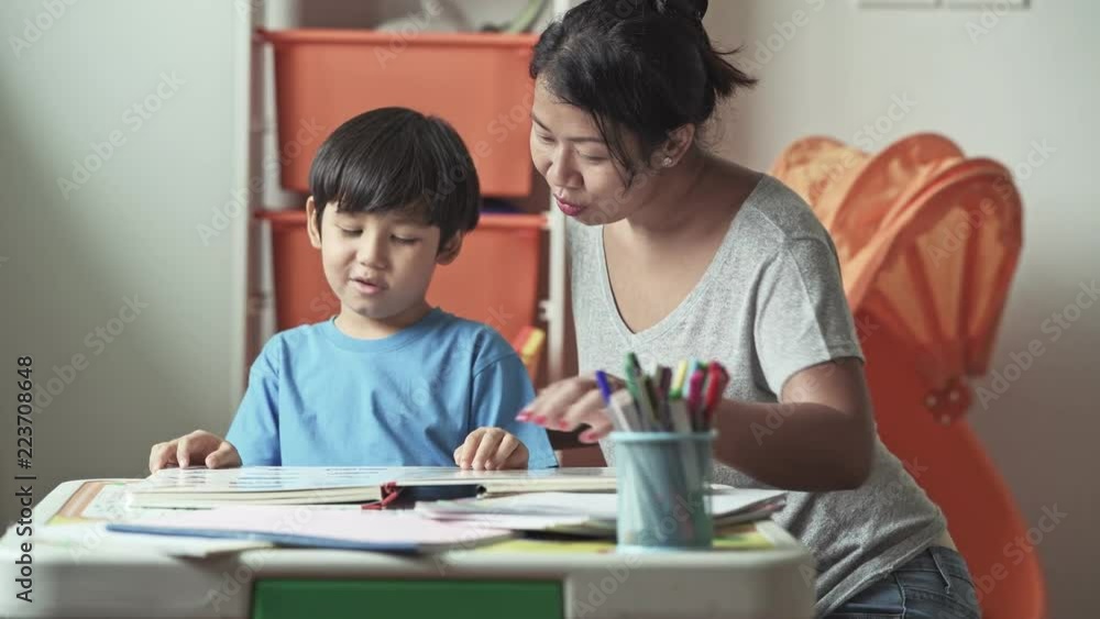 Children homework. Young mixed race boy doing homework in terrace at home. Reading book with his mother. Happy mood. Back to school concept. Children homework. Young mixed race boy doing homework in terrace at home. Reading book with his mother. Happy mood. Back to school concept.