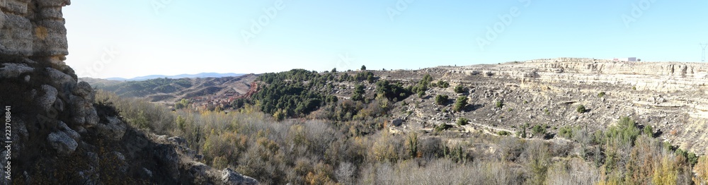 A landscape of the cultivated fields in a valley, with autumn colors, tilled earth, trees and a blue sky, around Anento, a small spanish village in the Aragonese Spain