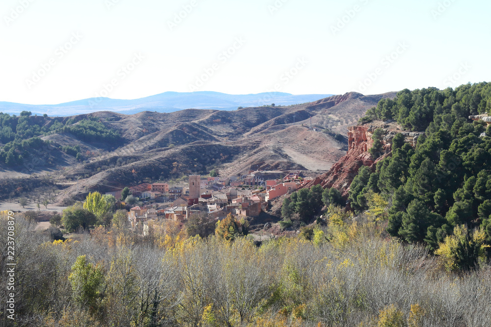 Obraz premium A landscape of the cultivated fields in a valley, with autumn colors, tilled earth, trees and a blue sky, around Anento, a small spanish village in the Aragonese Spain