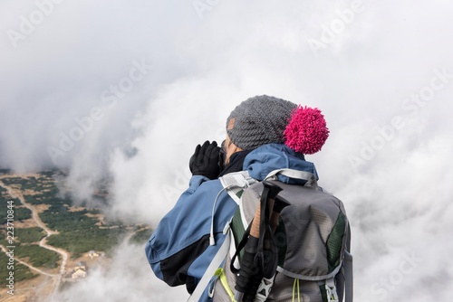 Trekking po górach z aparatem fotograficznym w chmurach. 