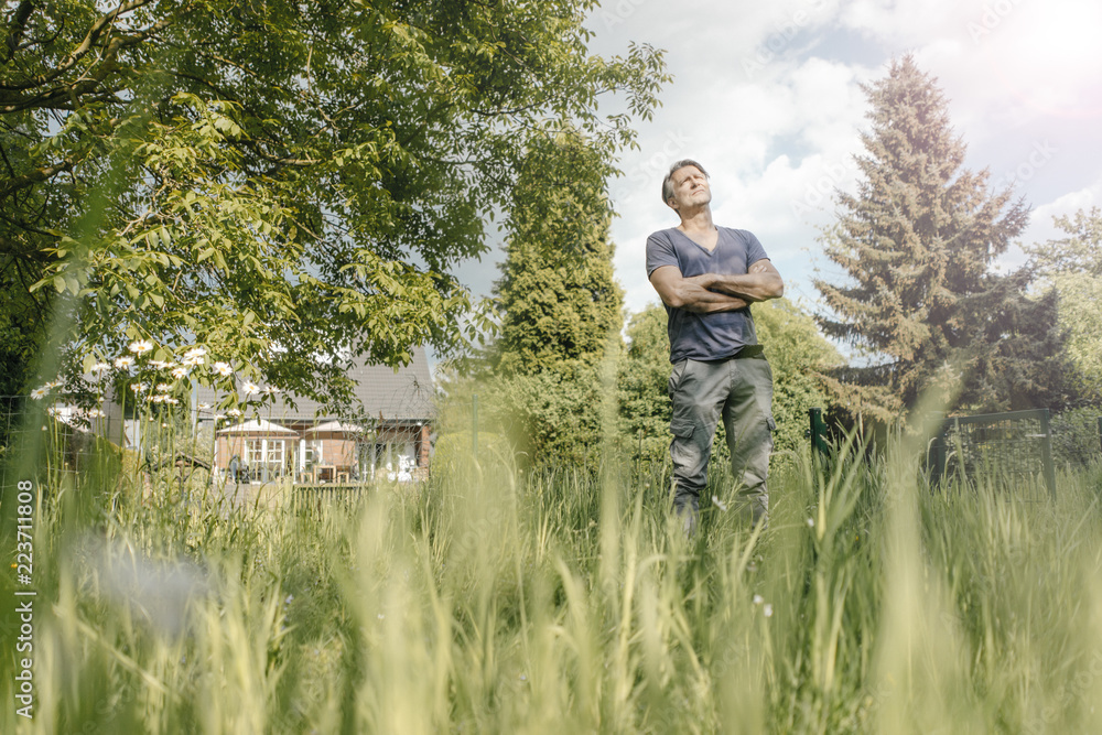 Mature man standing in garden of his home Mature man standing in garden of his home