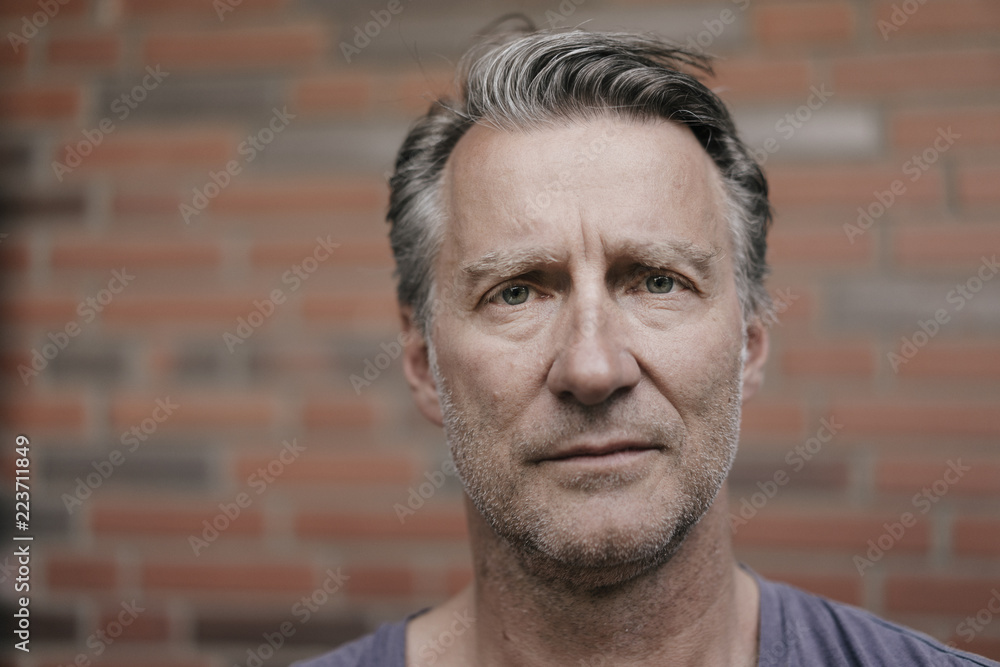 Portrait of serious mature man in font of brick wall Portrait of serious mature man in font of brick wall