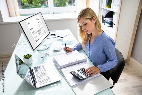 Young Businesswoman Calculating Bill In Office photo