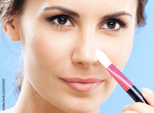 Woman with cosmetics brush, on blue