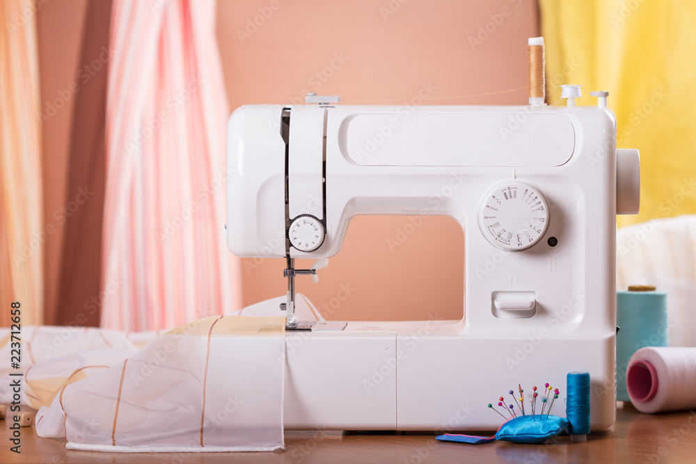 Workplace seamstress. White sewing machine, fabrics and accessories