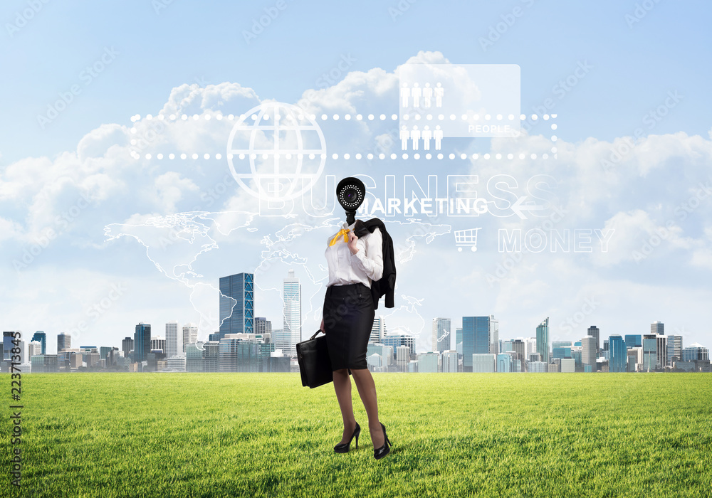 Camera headed woman standing on green grass against modern cityscape