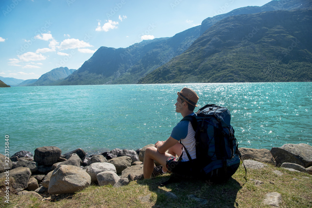 hiker with backpack resting near Gjende lake in Jotunheimen National Park, Norway