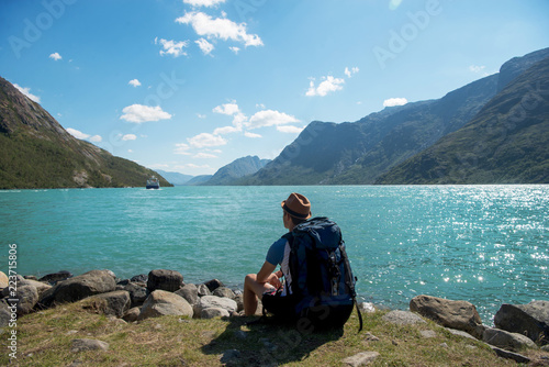hiker with backpack sitting and looking at Gjende lake in Jotunheimen National Park, Norway