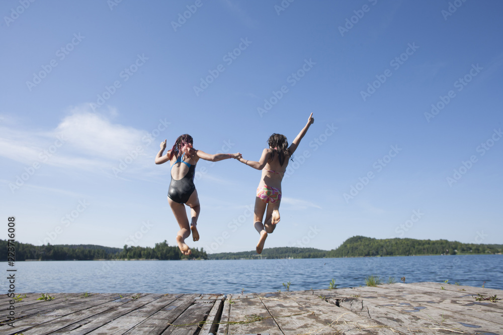 Preteen teens playing and jumping off a dock.