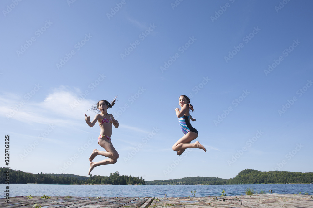 Preteen teens playing and jumping off a dock.