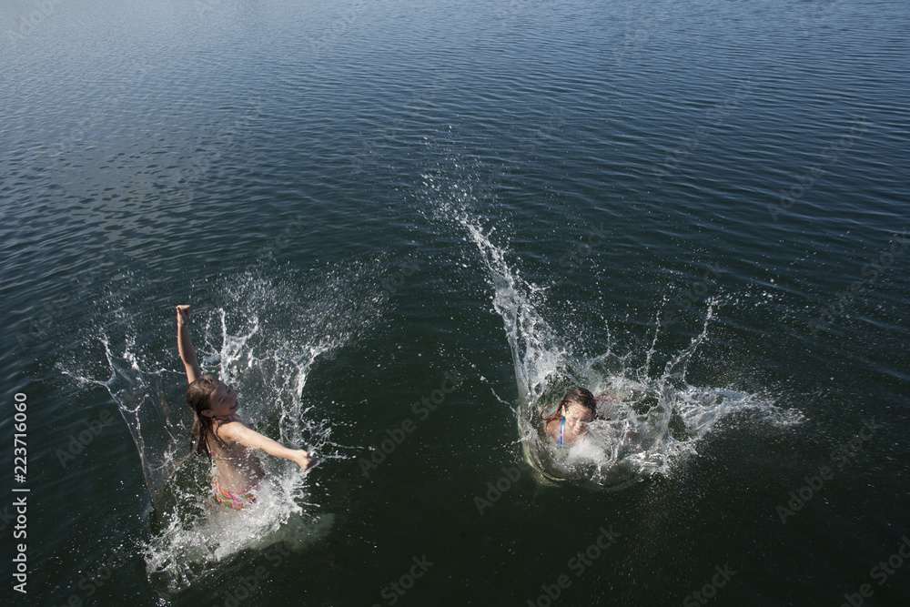 Obraz premium Twin girls jumping off dock.