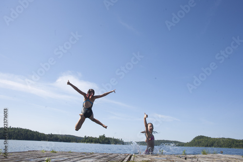 Preteen teens playing and jumping off a dock.