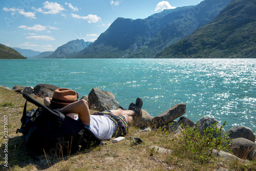 hiker resting on backpack near Gjende lake in Jotunheimen National Park, Norway photo