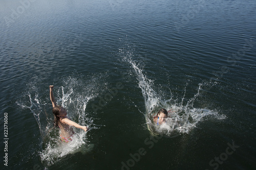 Twin girls jumping off dock.
