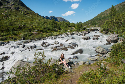 hiker sitting near mountain river on Besseggen ridge in Jotunheimen National Park, Norway