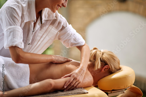 Smiling masseur is massaging a woman at spa close up.