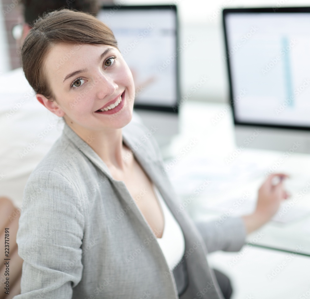 rear view. beautiful business woman sitting near the desktop and looking at the camera. rear view. beautiful business woman sitting near the desktop and looking at the camera.
