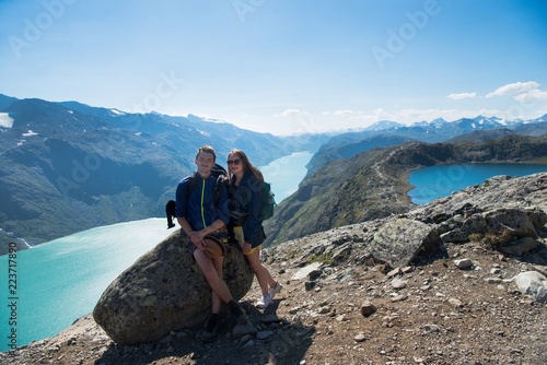 hikers resting on stone on Besseggen ridge over Gjende lake in Jotunheimen National Park, Norway