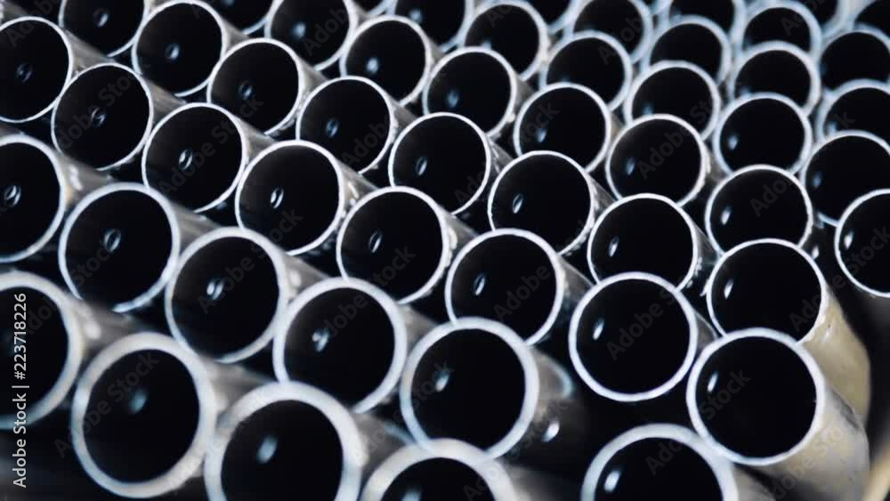 Metal profile pipe of round section in packs at the warehouse of metal products. Close-up of metal pipe. Warehouse for finished products of metal pipes of circular cross-section at the factory. Metal profile pipe of round section in packs at the warehouse of metal products. Close-up of metal pipe. Warehouse for finished products of metal pipes of circular cross-section at the factory.