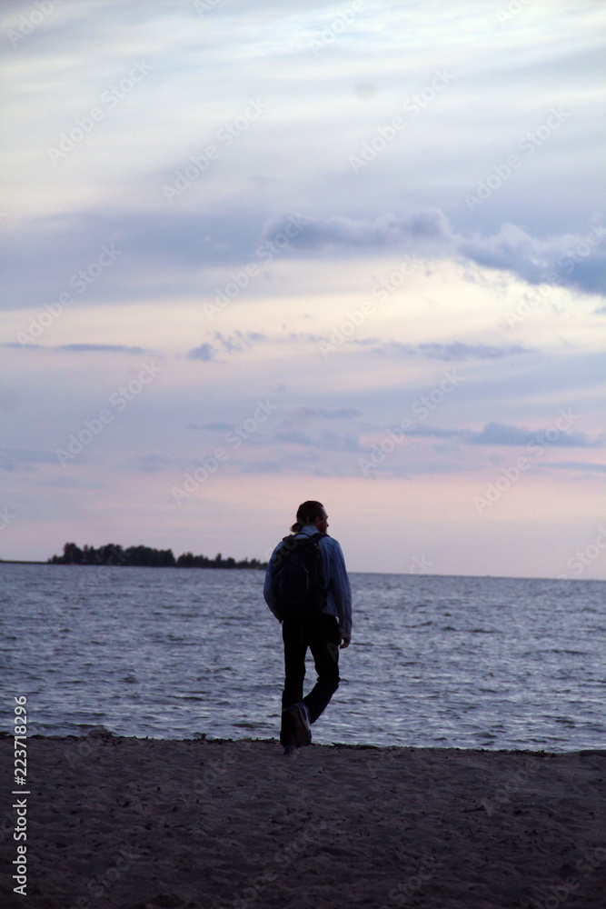 Pensive man walking along the shore.