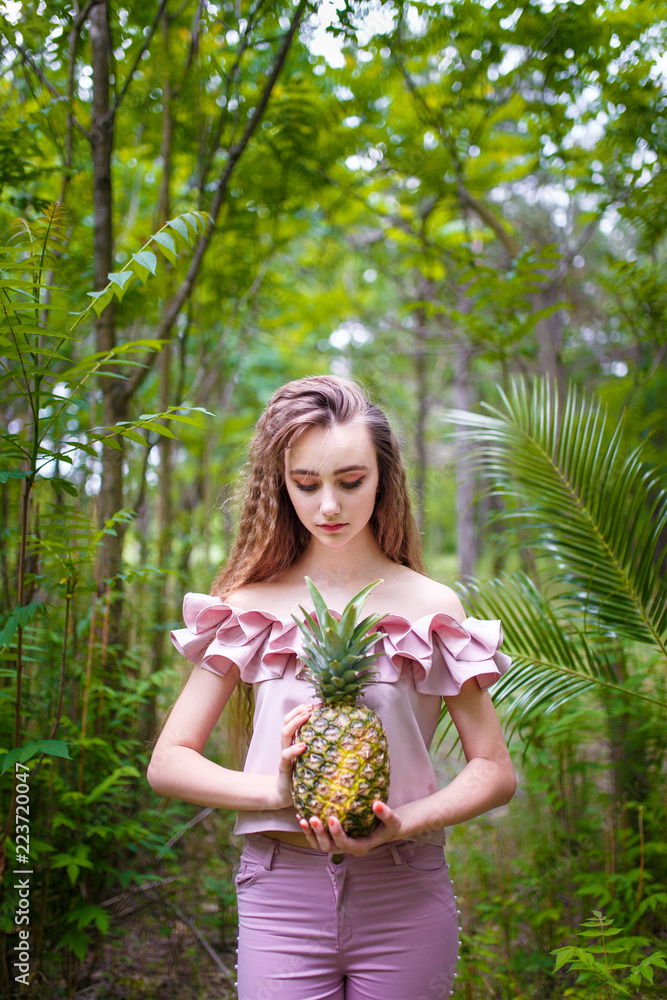 Obraz premium a young teenager girl in pink holding a pineapple