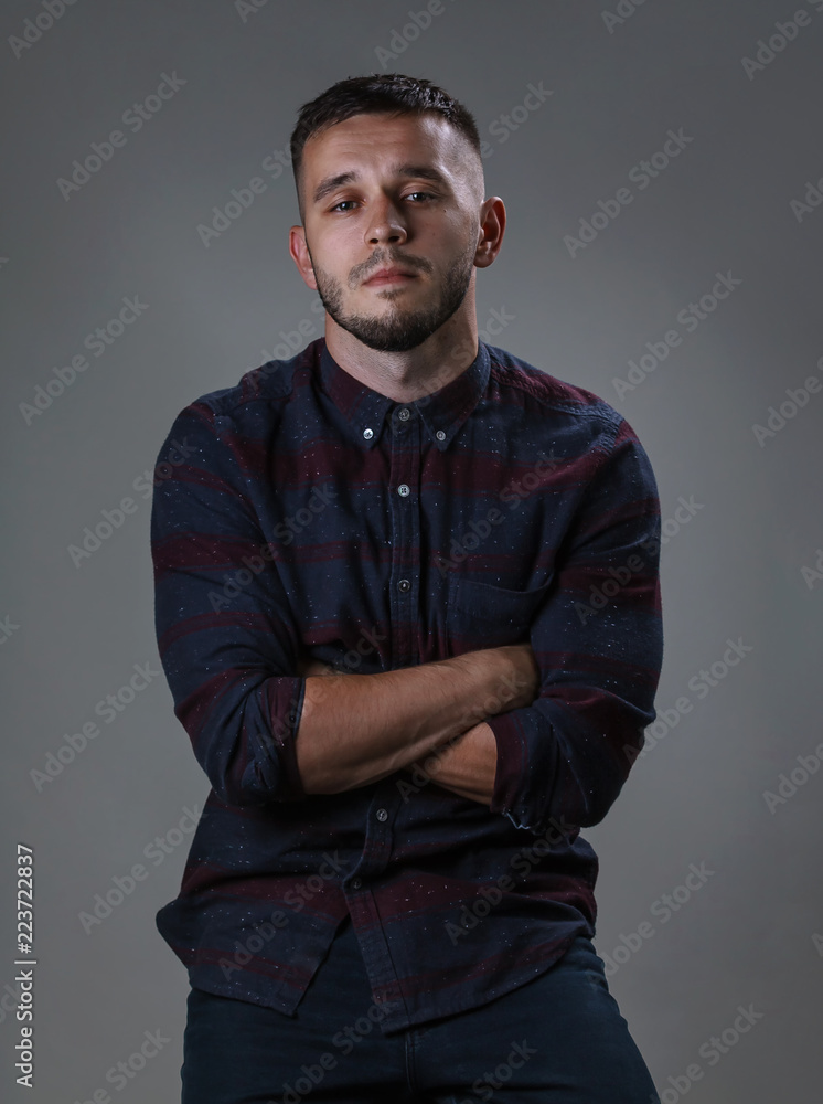 Obraz premium Man looking at camera. Portrait handsome in checkered shirt cross hands on breast. Copy space grey background
