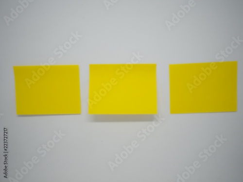 Three yellow sticky note stick horizontally on the white isolated wall