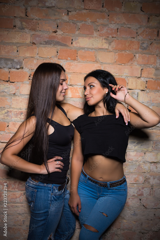 Two brunettes wearing black t-shirts and jeans