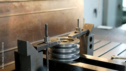 Private workshop, metal pulley installed in the drilling machine for further refinement, close-up, small business photo