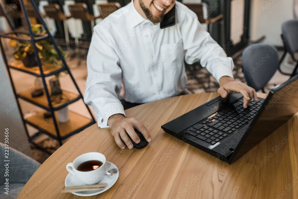 Happy businessman is speaking phone and printing on the laptop Happy businessman is speaking phone and printing on the laptop