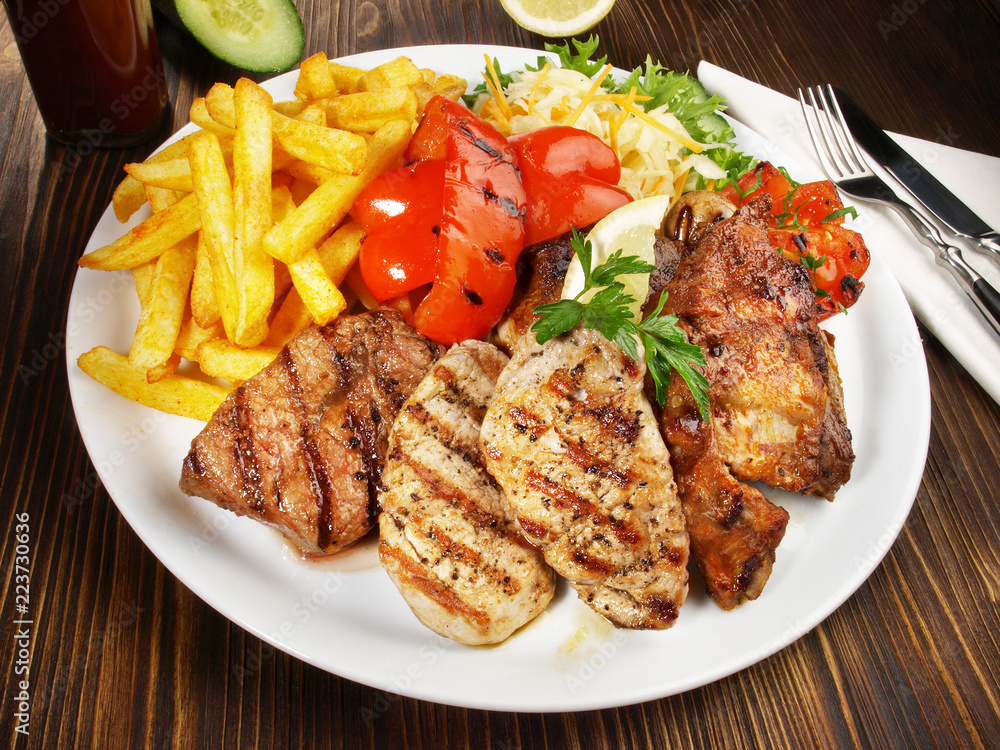 Grillteller mit Pommes Frites und Gemüse Grillteller mit Pommes Frites und Gemüse