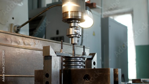 Tableau sur toile Drilling a hole with a drilling machine in a metal workpiece pulley, close-up, i