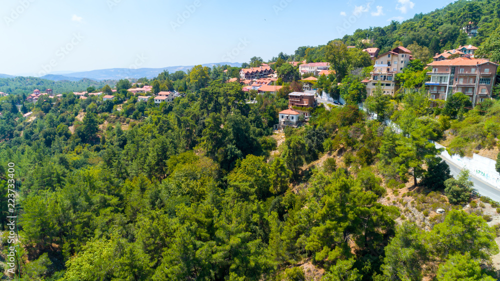 Aerial view of Pano Platres village,winter resort, on Troodos mountains, Limassol, Cyprus. Bird's eye view of pine tree forest, red roof tiled houses, hotels, panagias faneromenis church from above.