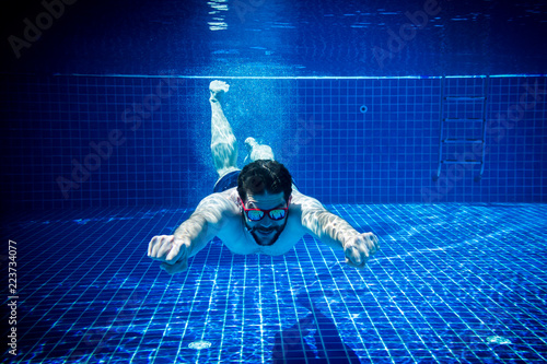 young man with sunglasses enjoying the swimming pool abstract summer fun underwater swimming jump diving background photo