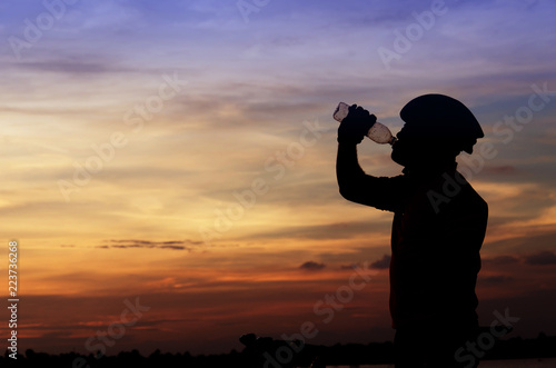 Close-up silhouette of the man drinking water with beautiful at sunset