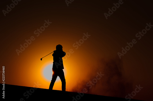 Silhouette male golfers are golfing with warm light of sunset