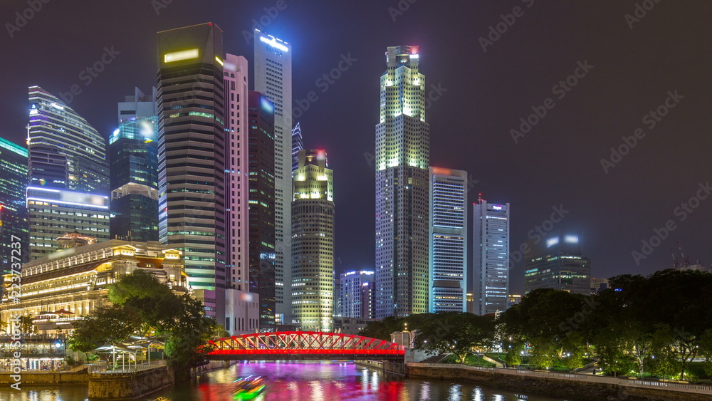 Fototapeta premium A view of Singapore business district skyscrapers in the night time with water reflections timelapse hyperlapse