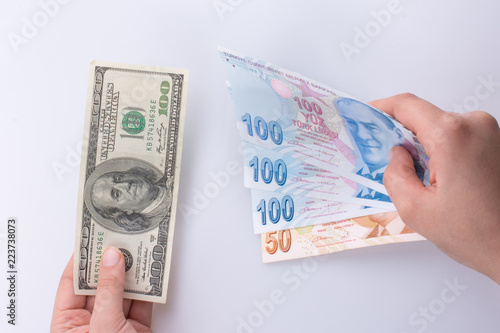 Hands holding American dollar banknotes and Turksh Lira banknotes side by side photo