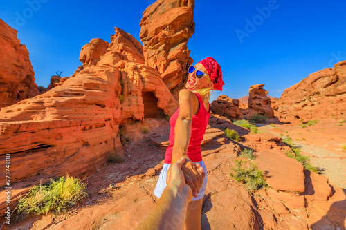 Follow me, happy young sporty girl holding hands at Firecave, the rock formations in Valley of Fire State Park, Nevada, USA. Concept of the journey of woman tourist traveler, holding man by hand. photo