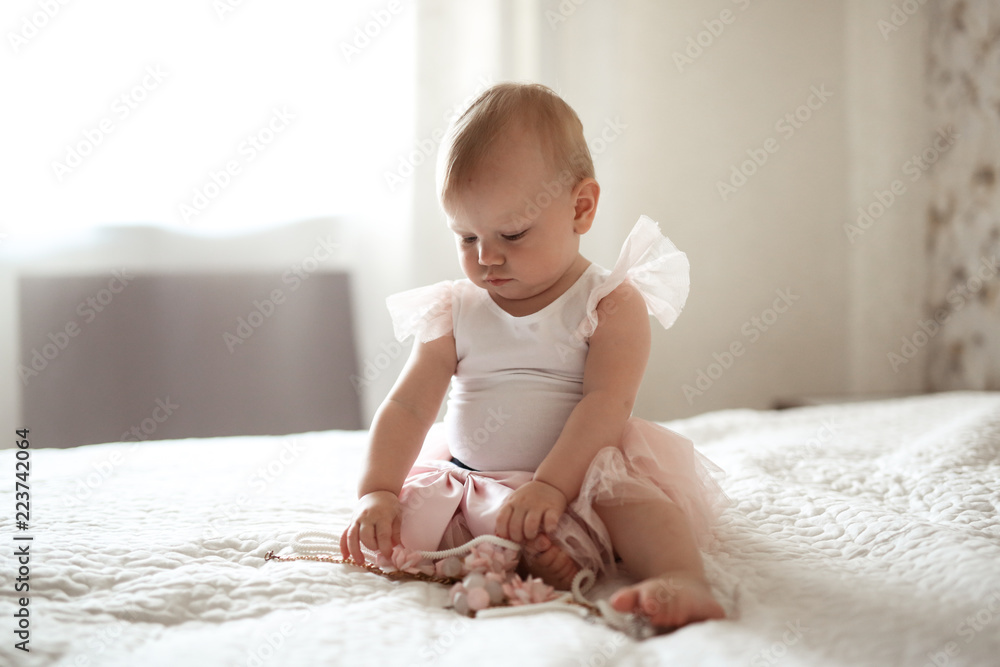 Toddler baby in dress playing,bed in real interior