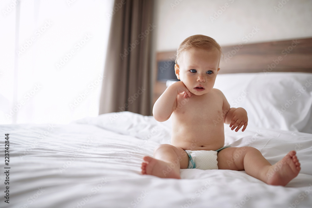 Adorable boy in white bedroom. child relaxing in bed.. Adorable boy in white bedroom. child relaxing in bed..