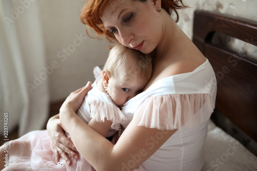 cute mother breastfeeding toddler daughter on bed