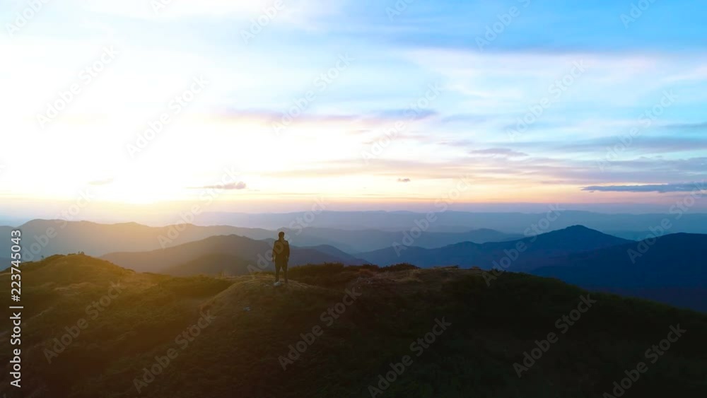 The happy male standing on the top of the mountain with a picturesque landscape The happy male standing on the top of the mountain with a picturesque landscape