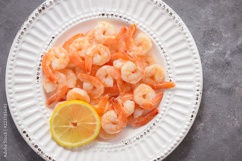 Cooked shrimps on the white plate with lemon. Cooked shrimps on the white plate with lemon.