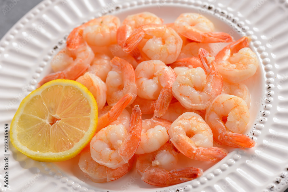 Cooked shrimps on the white plate with lemon. Cooked shrimps on the white plate with lemon.