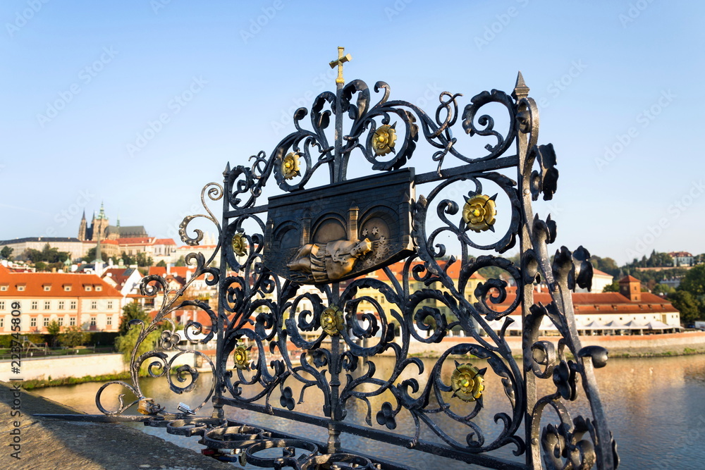 Decorative lattice with John of Nepomuk bronze statue on Charles Bridge, Prague, Czech Republic, sunny day