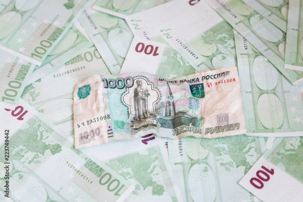 Obraz premium Crumpled banknote of one thousand rubles against the background of hundreds euro banknotes