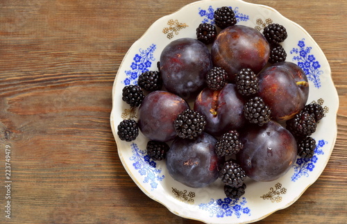 Fresh dark fruits and berries on a plate, top view, copy space photo